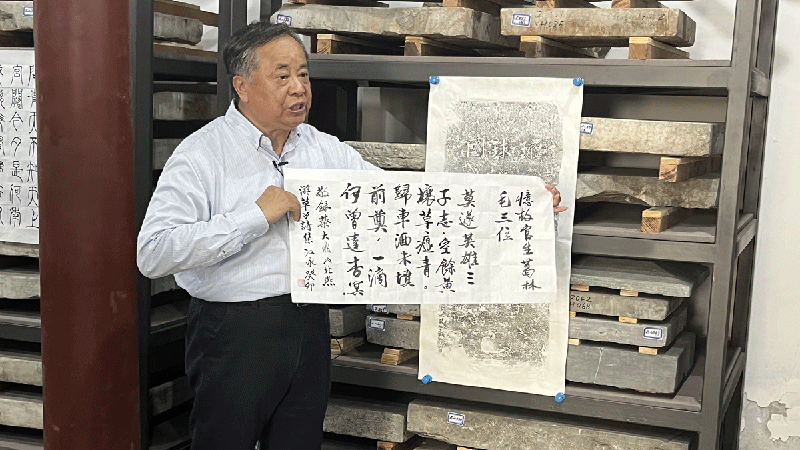 Liu Jiangyong holds a poem by a Ryukyuan student in front of a rubbing of the Ryukyu tombstone in Beijing's Tongzhou district. Photo: Xu Liuliu/Global Times