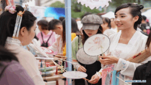 A girl wearing traditional Chinese clothing selects round fans in Kunming, southwest China's Yunnan Province, Aug. 7, 2019. Activities are held to display traditional Chinese clothing and reproduce ancient coming-of-age ceremony to celebrate the Qixi festival, or Chinese Valentine's Day, which falls on Aug. 7 this year. (Xinhua/Qin Qing)